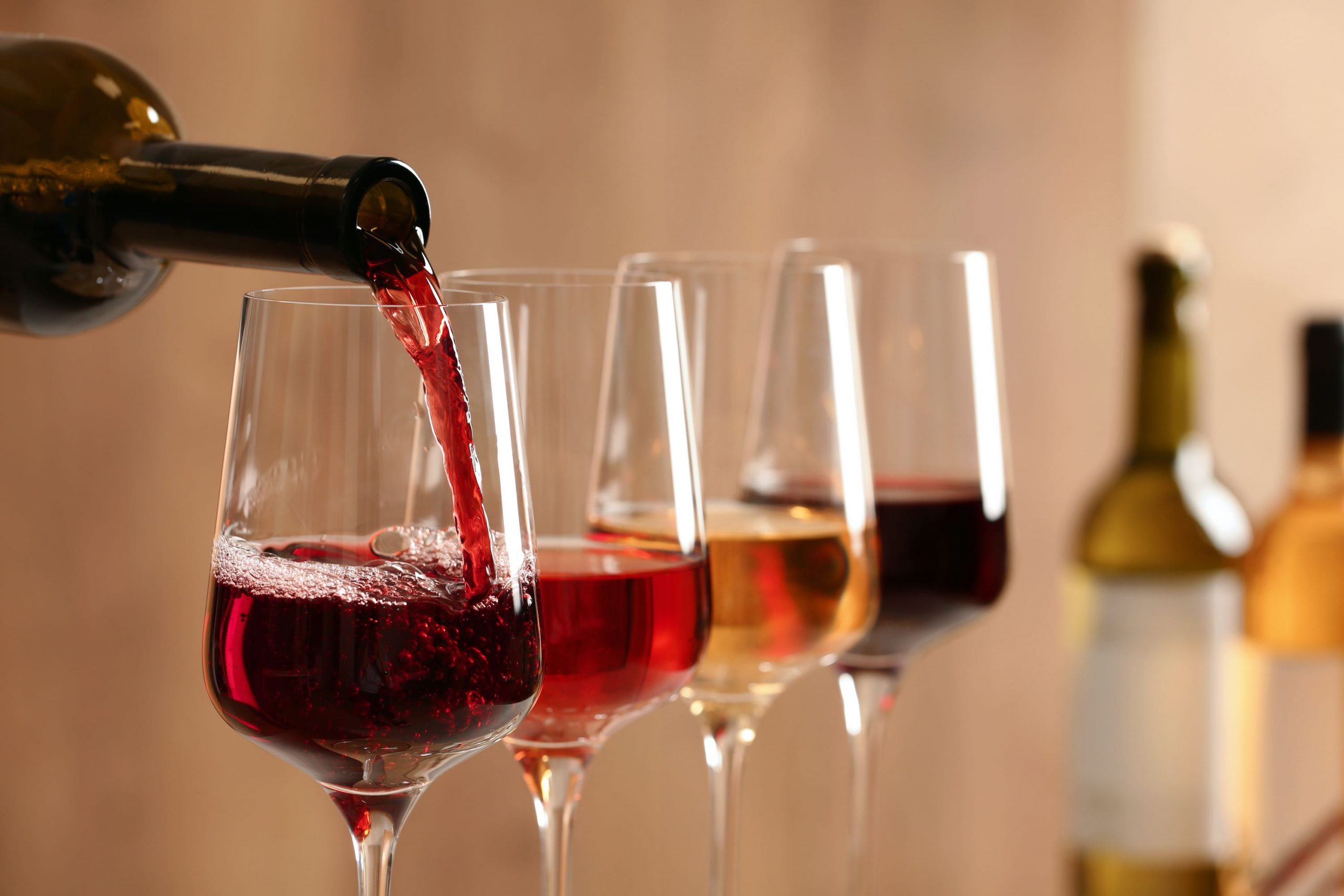 Pouring wine from bottle into glass on blurred background, closeup Wine and Wills